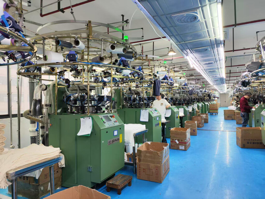 Rows of circular knitting machines and yarn feeders in the Yiwu workshop